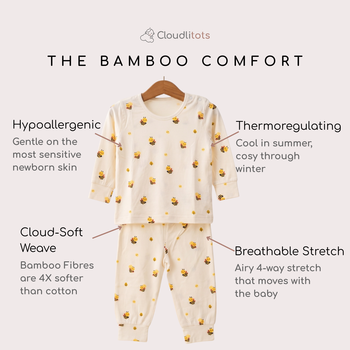 A baby bamboo lounge set consisting of a long-sleeve top and matching pants, displayed on a wooden hanger against a light beige background. The pajamas are cream-colored with a repeating pattern of small yellow and black bumblebees.