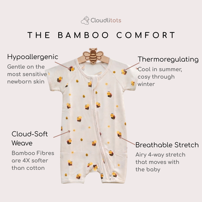 An off-white bamboo comfort bamboo romper with a yellow and black bee print, hanging on a wooden hanger with text callouts highlighting its hypoallergenic, thermoregulating, stretch, and soft fabric qualities. The brand name 'Cloudlitots' is visible at the top.