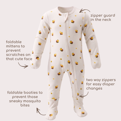 A baby footed one-piece bamboo sleepsuit in cream with a bee print, shown with callout arrows and text explaining features like the zipper guard, foldable mittens, foldable booties, and two way zippers.