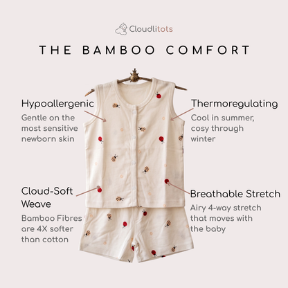 A baby sleepwear set consisting of a sleeveless jabla and matching shorts in a light cream color with small red ladybug motifs, displayed on a hanger against a light beige background with descriptive text callouts.