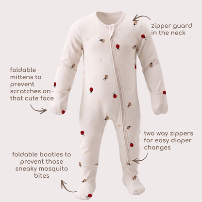 A baby one-piece bamboo sleepsuit in off-white with a ladybug print, featuring callout arrows and text explaining its features like foldable mittens, zipper guard, and booties.