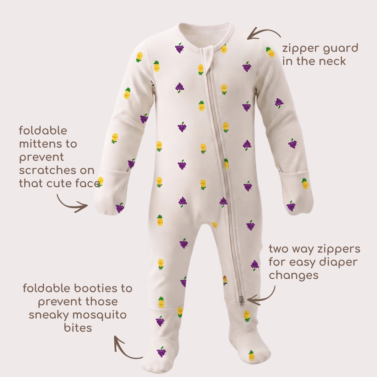 A baby bamboo sleepsuit with a white base and a pattern of small purple grapes and yellow pineapples, shown with callout arrows and text labels explaining its features.