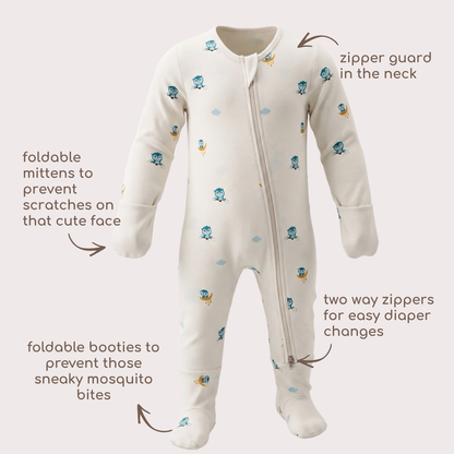 A baby bamboo sleepsuit with a white base and a pattern of small blue owl  and clouds shown with callout arrows and text labels explaining its features.