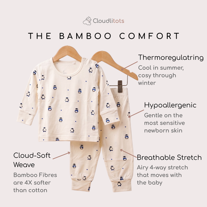 A two-piece baby bamboo lounge set displayed on wooden hangers against a light beige background, with text callouts highlighting features such as thermoregulating fabric, hypoallergenic softness, breathable stretch, and Cloud-Soft Weave. The set is cream-colored with a small blue penguin print.
