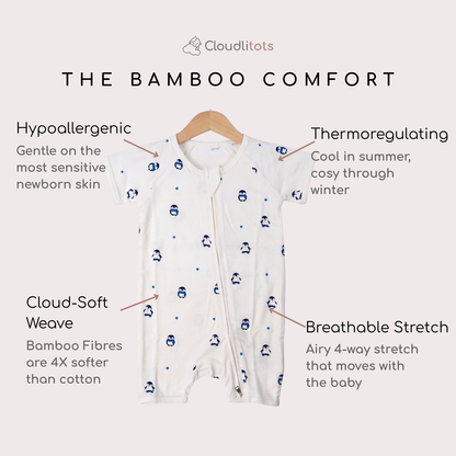 White short-sleeve baby bamboo romper with a front zipper and small blue penguin print, shown on a hanger with text callouts highlighting bamboo comfort features.